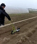 Person using Garden Seed Spreader Manual Seeder Handheld Planter For Peanut Corn Beans Seeds Easy To Use Garden Farm Tool Three Row Spreader With Durable Portable Design For Small Plots on farm soil.