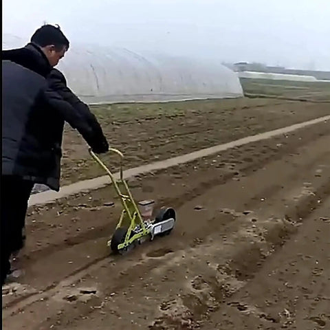Person using Garden Seed Spreader Manual Seeder Handheld Planter For Peanut Corn Beans Seeds Easy To Use Garden Farm Tool Three Row Spreader With Durable Portable Design For Small Plots on farm soil.