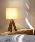 Wooden Tripod Table Lamp With Brown Base And Linen Fabric Shade on nightstand, space saving light for bedroom, cozy ambience