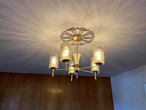 Chandelier with frosted glass shades illuminated, mounted on ceiling, casting light patterns. Not the exact product described.