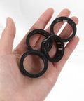 Hand holding 15 Pcs Round Cable Snap Grommets One And A Quarter Inch Thirty Two Millimeter Plastic Cable Hole Grommets For Wiring Black