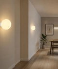 Minimalist Globe Wall Sconce, 1-Light White E27 Round Wall Light Fixture illuminating a modern hallway with soft light.