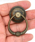 Close-up of a single vintage antique brass drop ring pull for drawers, large ring size 1.4-inch, shown in a hand.