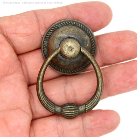 Close-up of a single vintage antique brass drop ring pull for drawers, large ring size 1.4-inch, shown in a hand.