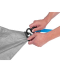 Hands securing Heavy Duty Camping Tarp 8x10 Feet Weatherproof Shelter For Outdoors with blue strap and grommet