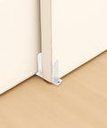 Sliding closet door with white acrylic floor guide, part of 4-Piece Sliding Closet Door Floor Guides Set In White Acrylic, Practical Bottom Guides For 1-3/8 Inch Thick Doors, Includes 8 Screws And Expansion Plugs For Smooth Sliding In Cloakrooms, Bathrooms And Kitchens, installed on light wood floor.