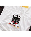 Close-up of a white cycling jersey featuring a black eagle emblem and the word 'MUBODO' in red and yellow.
