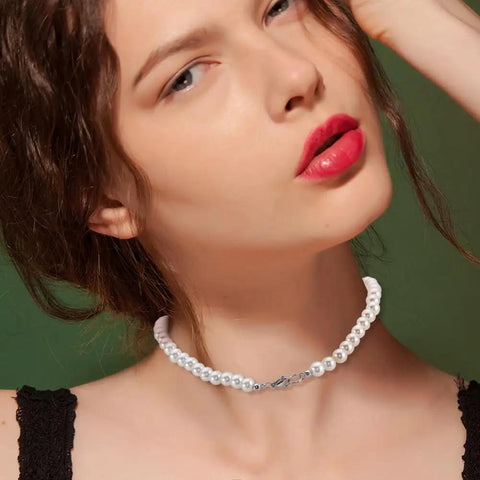 Model wearing a white pearl necklace showcasing a jewelry accessory with a simple clasp on green background