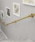 Rock Solid Wrought Iron Grab Rail 1ft Banister Support Bracket in gold, mounted on a wall near stairs for safety grip.