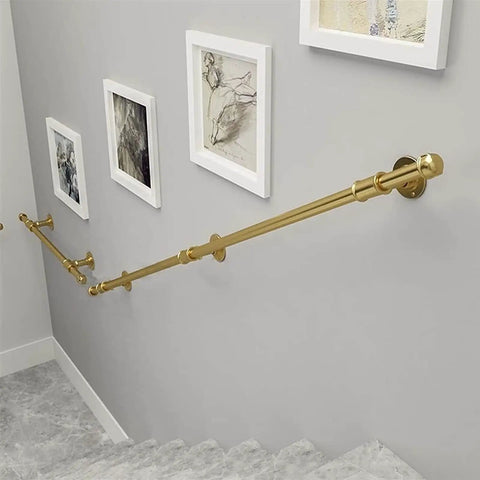 Rock Solid Wrought Iron Grab Rail 1ft Banister Support Bracket in gold, mounted on a wall near stairs for safety grip.