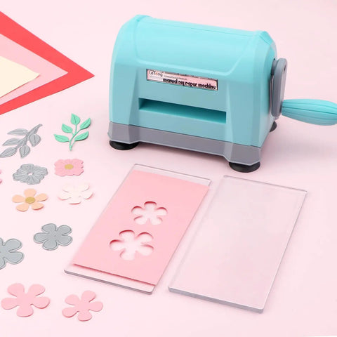 Portable Die Cutting And Embossing Machine For Card Making And Scrapbooking No Fuss Mini Cutter For Paper Crafting Easy Manual Operation Works With Dies And Folders Up To 3 Inches Wide shown with flower die cutouts on pink surface