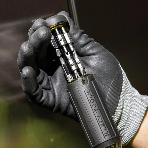 Gloved hand holding Grab And Go Multi Bit Tamperproof Screwdriver Kit With Twenty Six Onboard Bits And Quarter Inch Nut Driver Built