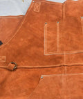 Close-up of brown leather welding apron with flame resistant shield and six tool pockets, built to last.