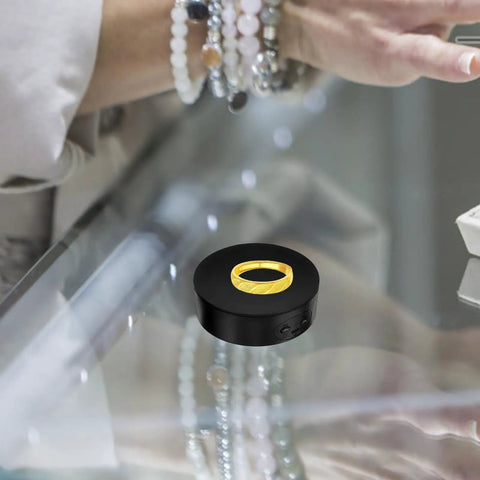 Electric Rotating Jewelry Display Stand showcasing a gold ring on a black turntable, with a hand in the background.