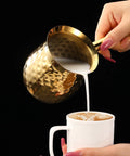 Gold Hammered Stainless Steel Turkish Coffee Cezve 7 Oz 200 Ml Ibrik With Heat Resistant Handle pouring milk into coffee cup