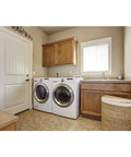Laundry room with washer and dryer next to wooden cabinets and wicker basket.