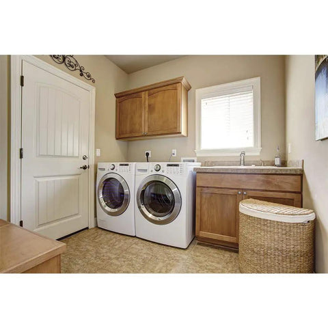 Laundry room with washer and dryer next to wooden cabinets and wicker basket.