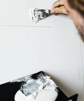 Worker using Stiff One And A Quarter Inch Putty Knife For Light Duty Construction And Home Projects Carbon Steel Blade For Easy Spreading And Cleanup DIY Series Budget Friendly Pro Grade Ideal For Drywall Patching And General Finishing Projects on wall with white compound.