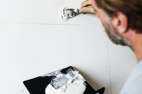 Action shot of One And A Half Inch Carbon Steel Flex Putty Knife From Painters Series used for smooth spackle on wall surface.