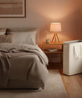 Space Saving Skinny Laundry Basket For Narrow Spaces With Durable Handles in bedroom setting next to nightstand, 48L Beige
