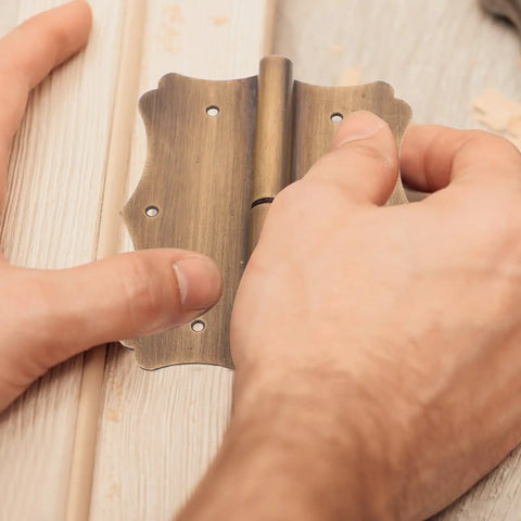 Hands installing heavy duty copper door hinge with vintage edge, rust resistant, focusing on stability and security.