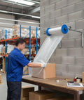 Person using Wall Mounted Bubble Wrap Dispenser For Packing And Shipping in warehouse, holder fits various widths on concrete wall.