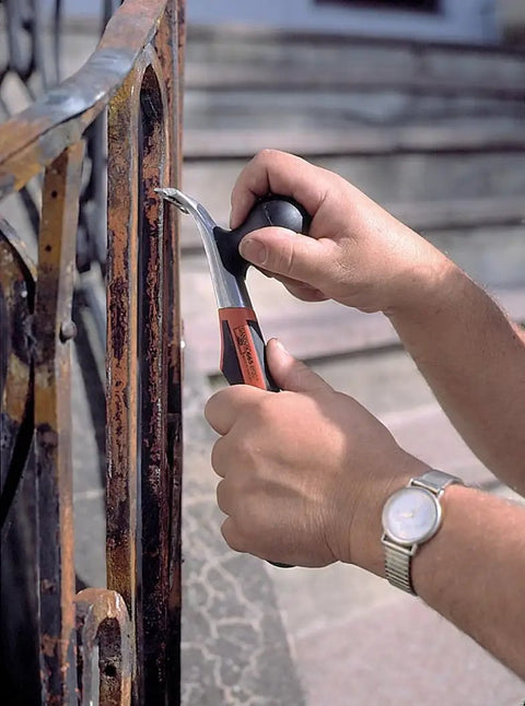 Hands using Heavy Duty Carbide Blade Scraper With 2.5 Inch Wide Blade, Ergonomic Handle on rusty metal railing.