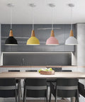 KCEYANB Adjustable Height Pendant Light Modern Simplicity Metal Hanging Lamp in black, yellow, pink, and white above a dining table.