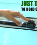Touch 'n Hold dual door closer, black cylindrical unit mounted on storm door frame; hand presses hold-open