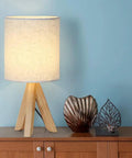 Set Of 2 Wood Tripod Bedside Lamps With Linen Fabric Shade on wooden nightstand next to decorative items.
