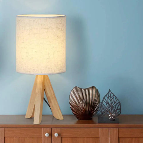 Set Of 2 Wood Tripod Bedside Lamps With Linen Fabric Shade on wooden nightstand next to decorative items.