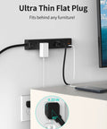 Wall-mounted Ultra Thin Flat Plug Power Strip with 6 outlets and 3 USB ports beside a desk, fitting snugly behind furniture.