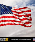 Waving American flag on flagpole against cloudy sky background with "Hero's Pride" logo at the bottom.