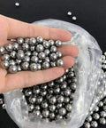 Heavy Duty G10 Steel Bearing Balls In 6.35mm Or 1 4 Inch Diameter held in hand, showing smooth shiny surface and bulk package.