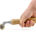 Hand holding Brass Seam Roller For Roofing And Vinyl Flooring Detail Roller With Wood Handle Durable Brass Construction And Smooth Bearing
