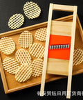 Manual stainless steel wave cutter for crinkle-cut potatoes and vegetables; wooden frame with orange guide.
