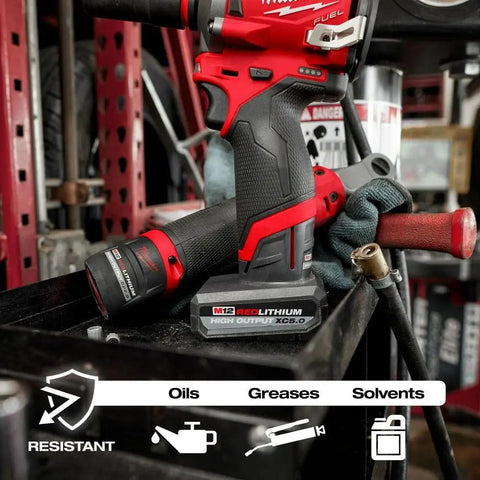 M12 RedLithium High Output 2.5Ah Battery with drill in workshop setting, resistant to oils, greases, and solvents