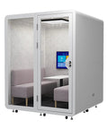 Roll Straight Up Anywhere With This Mobile Office Pod Booth Featuring Actually Sound Proof Walls Integrated Led Lighting Handy Usb Ports And Smooth Caster Wheels Setting Up A Quiet Coworking Nook For Up To Four Crew Indoors Or Outdoors with two couches and a table inside.