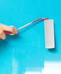 Person using a 6 Piece Paint Roller Set Boasting Hella Soft Sponge Covers And Comfort Grip Handles on blue wall.