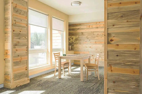 Room interior with light gray vinyl wall base and natural wood paneling, featuring a small table and chairs under soft lighting.