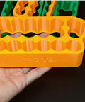 Slick Heavy Duty Spot Welding Jig For 18650 And 21700 Battery Packs Safe Insulated Cell Holder in orange, holding 21700 cells.