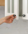 Hand opening cabinet door with Clear Self Stick Cabinet Bumper Pads Twenty Pack Round One Half Inch Rubber Cushions visible on knob