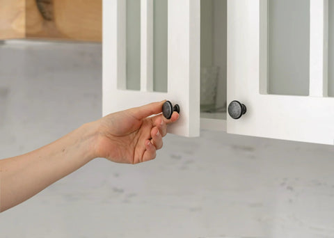 Hand opening cabinet door with Clear Self Stick Cabinet Bumper Pads Twenty Pack Round One Half Inch Rubber Cushions visible on knob