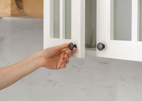 Hand opening cabinet showing Clear Self Adhesive Cabinet Bumper Pads 40 Pack Half Inch Round Rubber Door Bumpers Noise Dampening and Scratch Protection for Cabinets and Drawers Transparent Protectors with Easy Install Non Slip Cushions