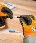 Close-up of hands assembling Klein Tools 56025 non-conductive fish tape repair kit; orange gloves