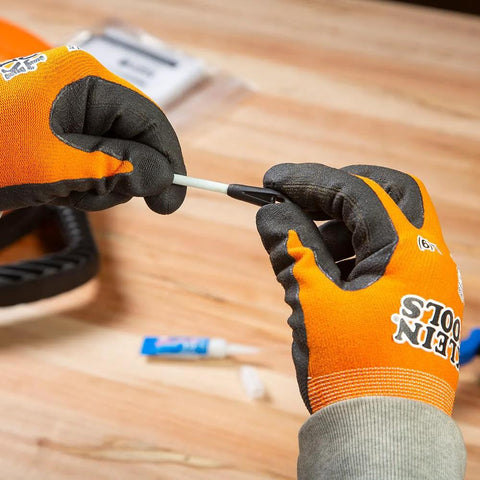 Close-up of hands assembling Klein Tools 56025 non-conductive fish tape repair kit; orange gloves