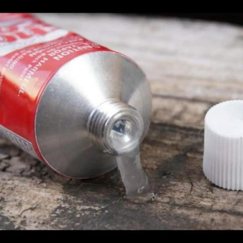 Shoe Goo Specialty Sealant And Glue 3.7 Oz Tube Clear Finish for your kicks with glue oozing from tube, cap beside tube.