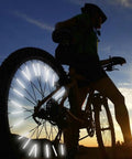 Cyclist silhouette with 72 Pcs Bicycle Spoke Reflective Strips For Night Riding 360 Degree Visibility illuminated at dusk