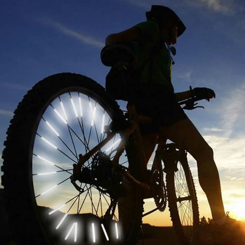Cyclist silhouette with 72 Pcs Bicycle Spoke Reflective Strips For Night Riding 360 Degree Visibility illuminated at dusk