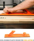 Orange push stick in use with rolling foldable table saw stand, aids in safe wood cutting, durable design for workshops.